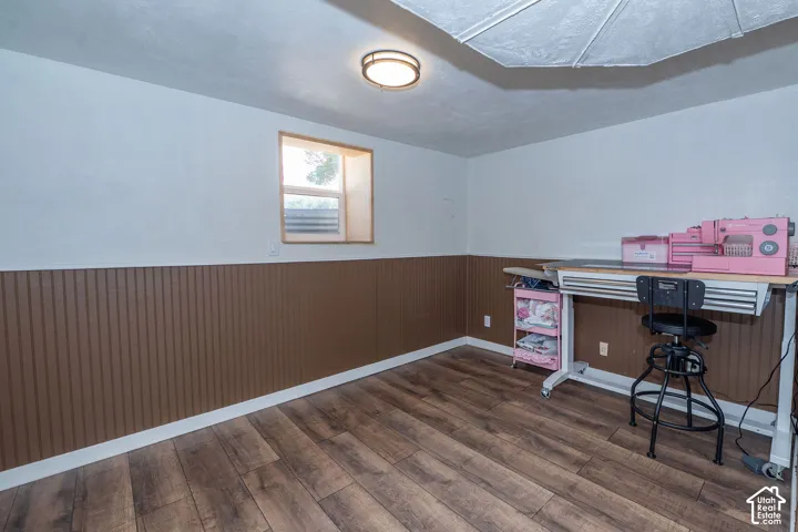 Wood-finish flooring with white baseboards, a window with wood trim, and a flush mount ceiling light
