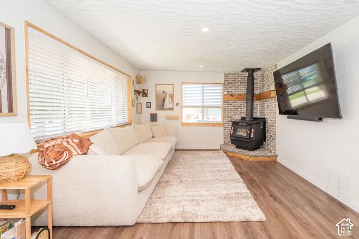 Wood-finish flooring, white walls, and a wood-burning stove with a brick surround