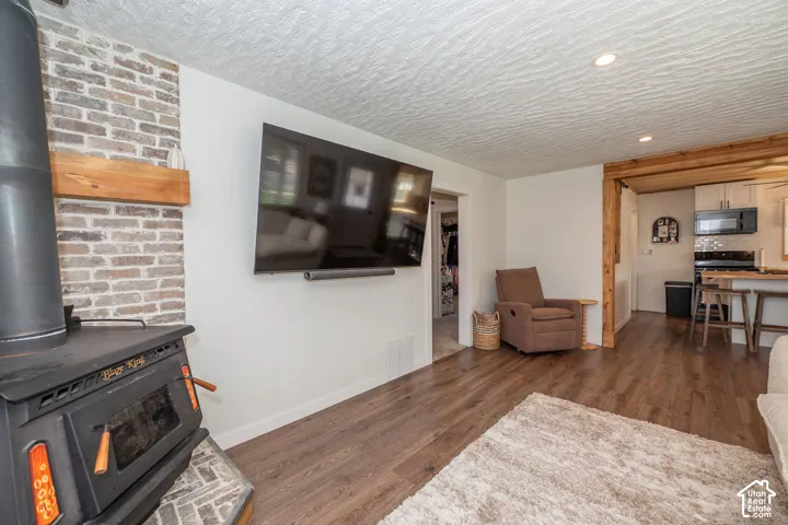 Wood-finish flooring, recessed lighting, and a wood-burning stove with a brick-clad wall
