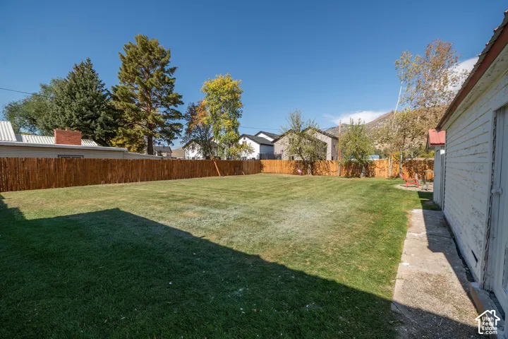 Expansive grass yard with a wood fence perimeter and a concrete walkway
