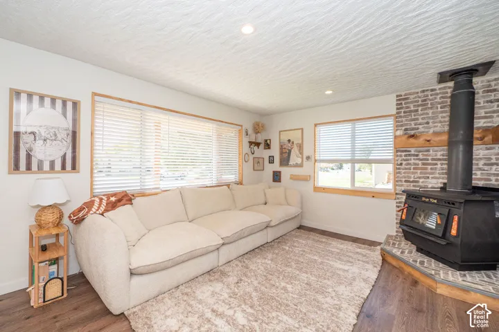 Wood-finish flooring with a brick-clad fireplace featuring a wood-burning stove