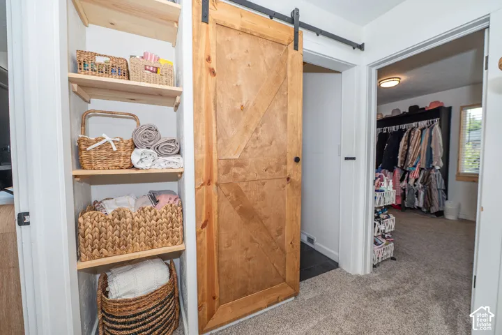 Wood-finish sliding barn door, integrated shelving, and carpeted flooring