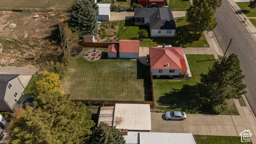 Property featuring a red metal roof, detached garage, and an expansive grassy lawn