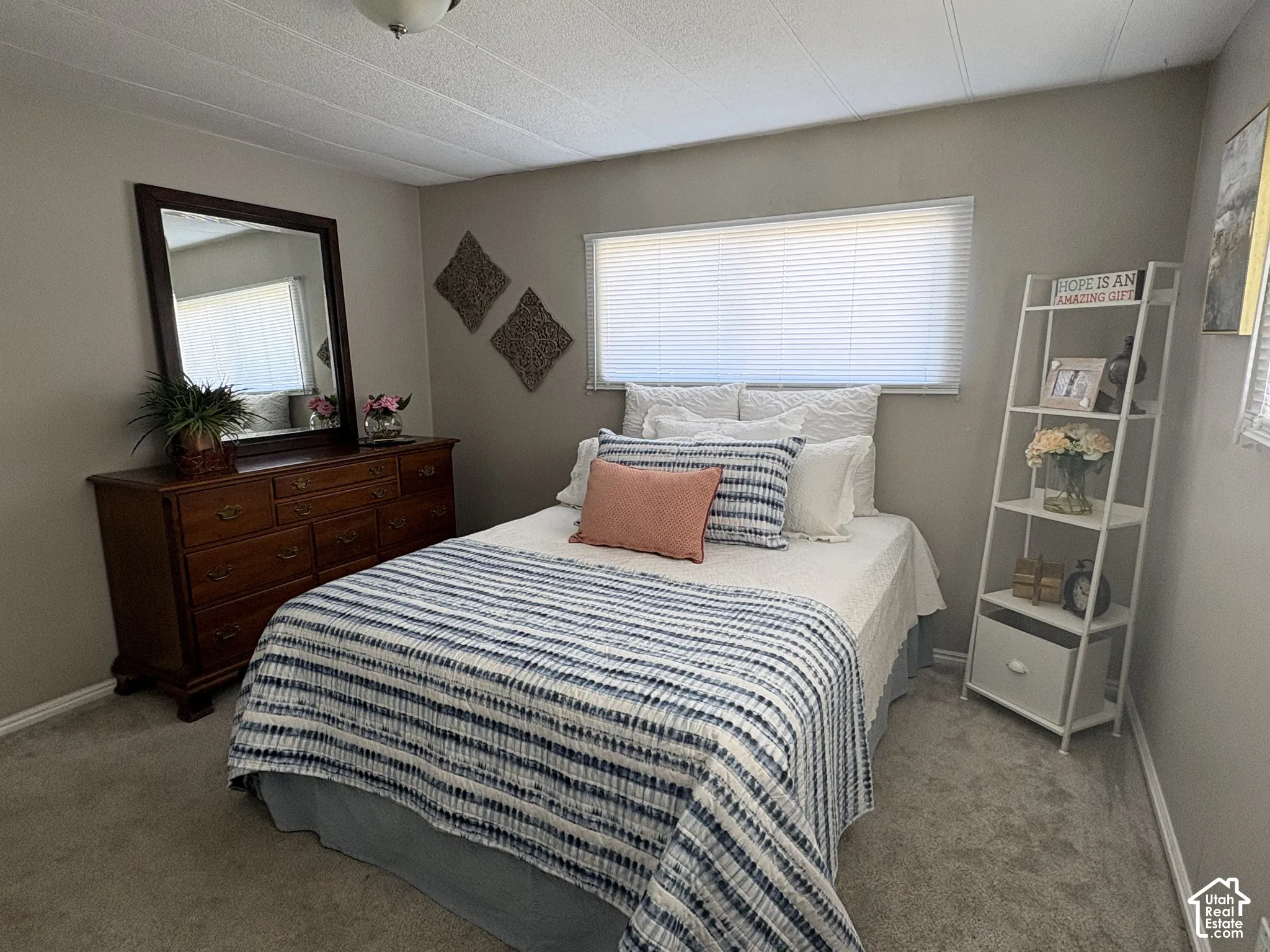 Carpeted flooring, window with blinds, wall-mounted light fixture, and neutral wall tones
