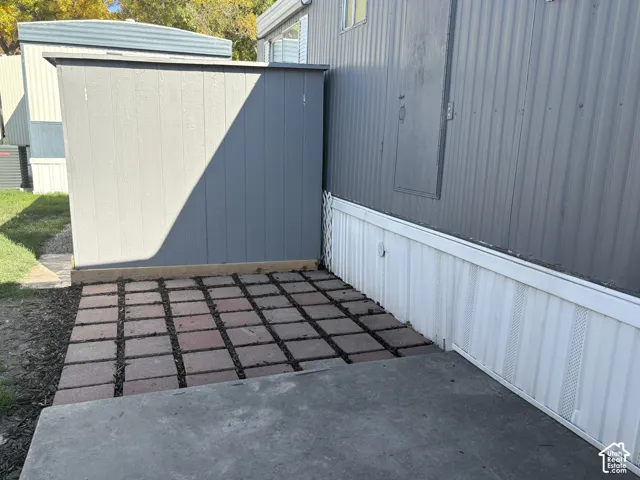 Paved patio area featuring concrete and brick pavers, a built-in storage shed, and horizontal siding