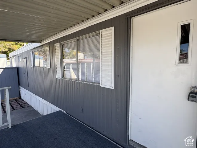 Corrugated exterior siding, multiple windows with louvered shutters, and an awning
