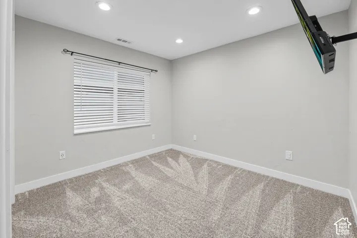 Neutral wall finishes with recessed lighting, window with blinds, and light-toned carpet flooring
