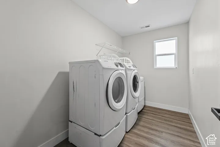 Utility room featuring wood-finish flooring, white walls, a single window, and a white wire shelf