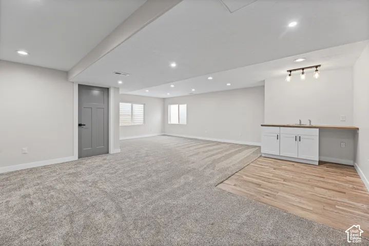 Spacious room with recessed lighting and a wet bar featuring white cabinetry and wood-finish countertops