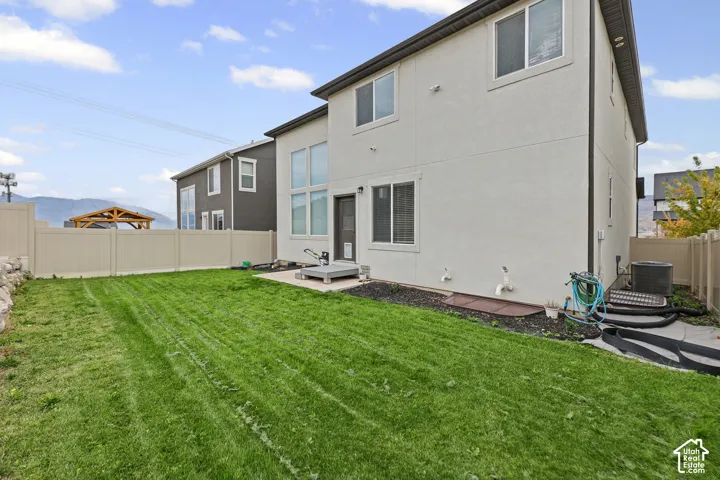 Rear exterior with a neutral-toned stucco finish, multiple windows, and a ground-level patio