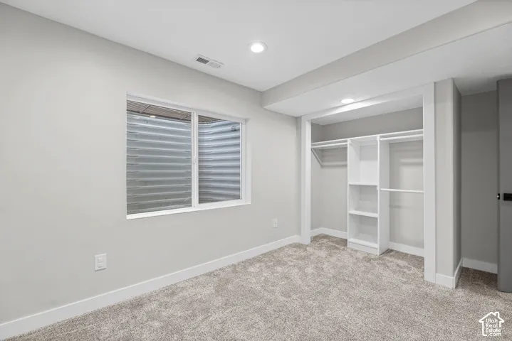 Recessed lighting, window with egress, built-in closet organization, carpet flooring, and white trim