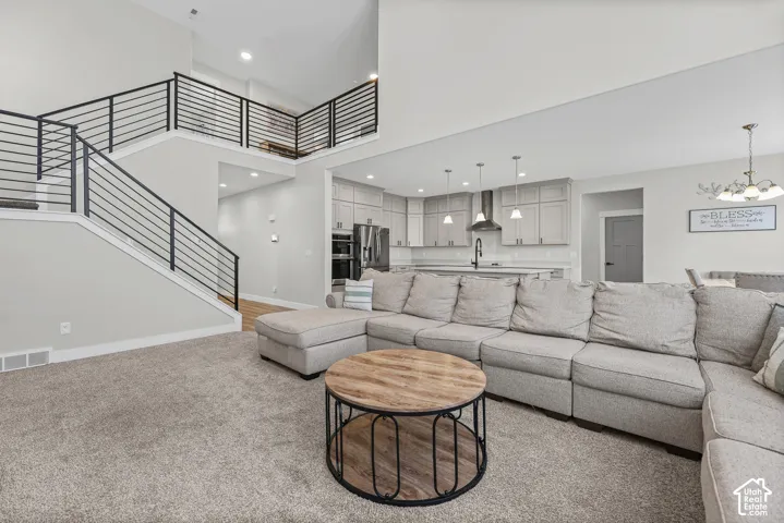 Open-concept living space with a kitchen, a two-story ceiling, a staircase featuring black metal railings, and wood-finish flooring in the kitchen area