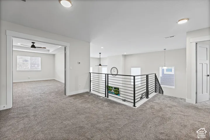 Open loft area featuring plush carpeting, a modern horizontal bar railing, and recessed lighting