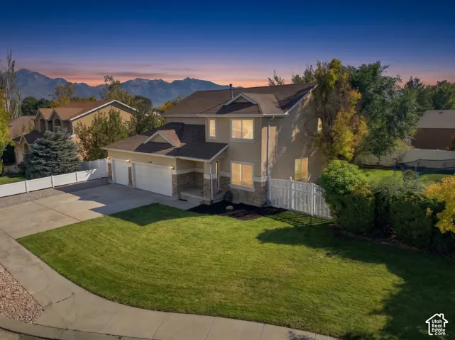 Two-story residence with a stucco and stone veneer exterior, a two-car garage, and a peaked shingle roof