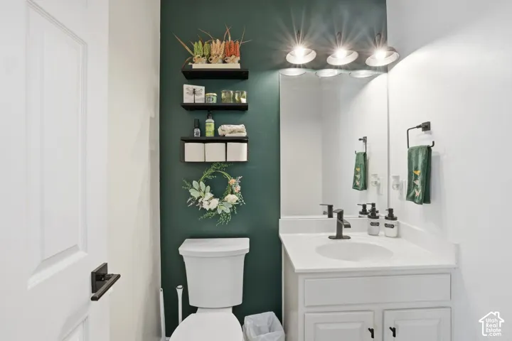 White vanity with a single basin and matte black faucet, wall-mounted mirror, and a three-light fixture
