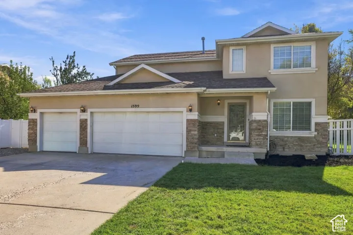 Stucco exterior with stone veneer accents, multi-pane windows, and a two-car garage
