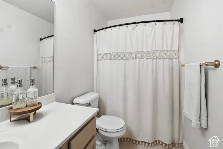 White walls, single vanity with light countertop, built-in mirror, toilet, and shower with a curved curtain rod