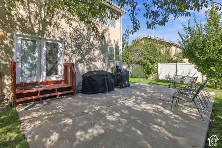 Concrete patio with a red-stained wood deck leading to glass-paneled double doors