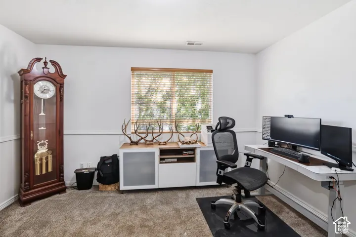 Window with wood-finish blinds, plush carpet flooring, white walls, and built-in white media console