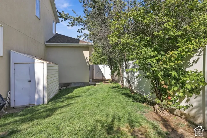 Manicured lawn with a storage shed, privacy fencing, and mature trees