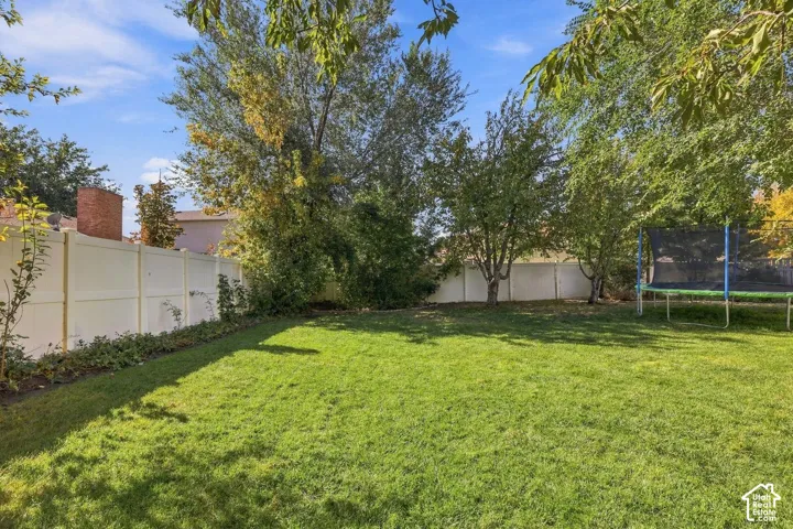 Expansive grassy lawn with mature trees and a perimeter fence