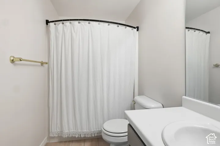 White vanity with integrated sink, toilet, and a shower area with a curved shower rod