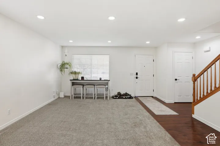 Recessed ceiling lighting, wood-finish flooring, white panel doors, wood staircase with balusters, and a window with blinds