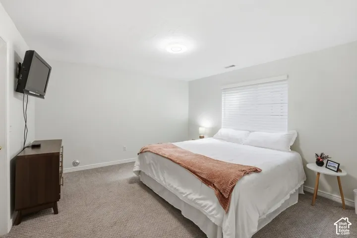 Recessed lighting, wall-mounted television, window with blinds, and neutral carpeting