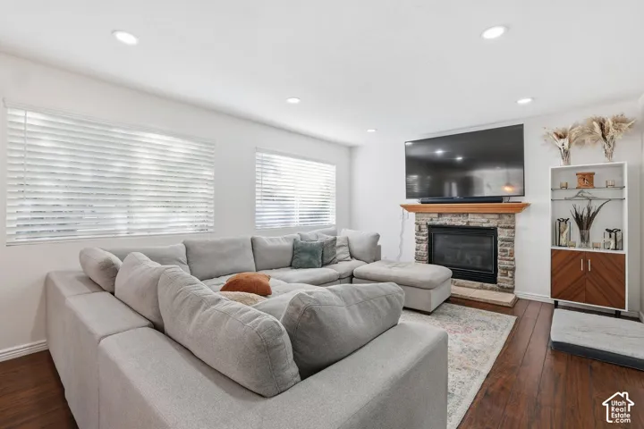 Living space featuring recessed lighting, dark wood-finish flooring, and a stone-clad fireplace with a wood mantel