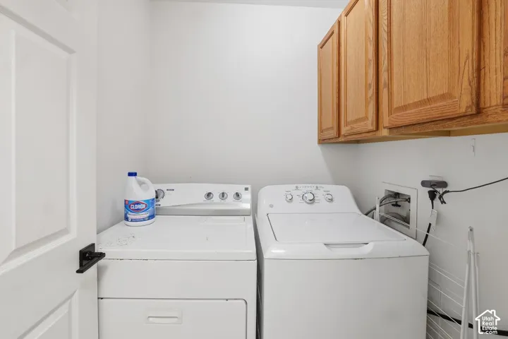 Laundry area featuring white walls, wood-finish cabinetry, and a white paneled door with black hardware