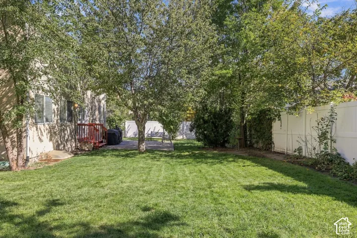 Expansive backyard featuring a lush lawn, mature trees, a private patio, and a privacy fence