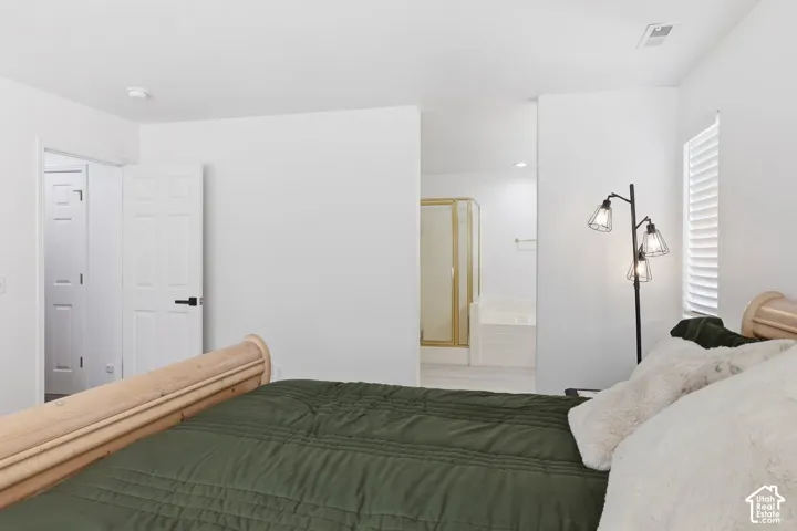 White paneled doors, window with horizontal blinds, and a partial view of a bathroom with a shower enclosure and built-in tub
