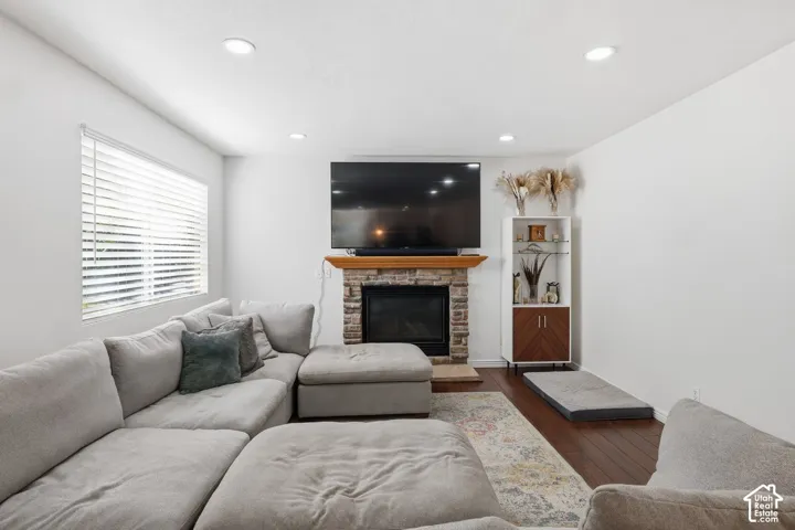 Integrated fireplace with a stone surround, wood-finish flooring, and recessed ceiling lighting