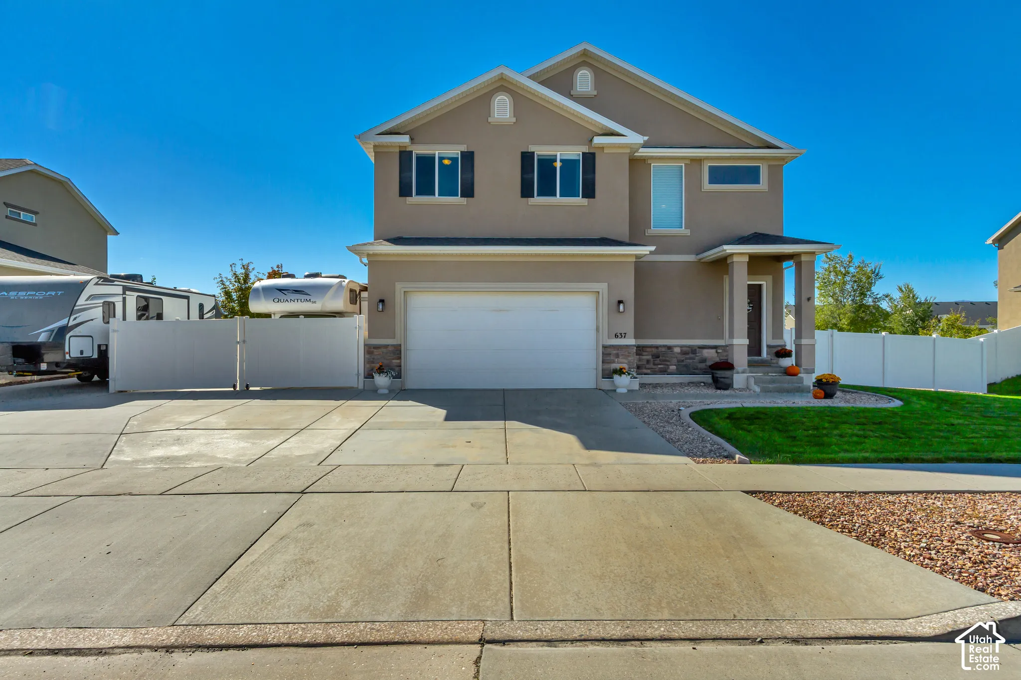 Two-story stucco exterior with stone accents, attached garage, covered entryway, and a private side yard with gated access