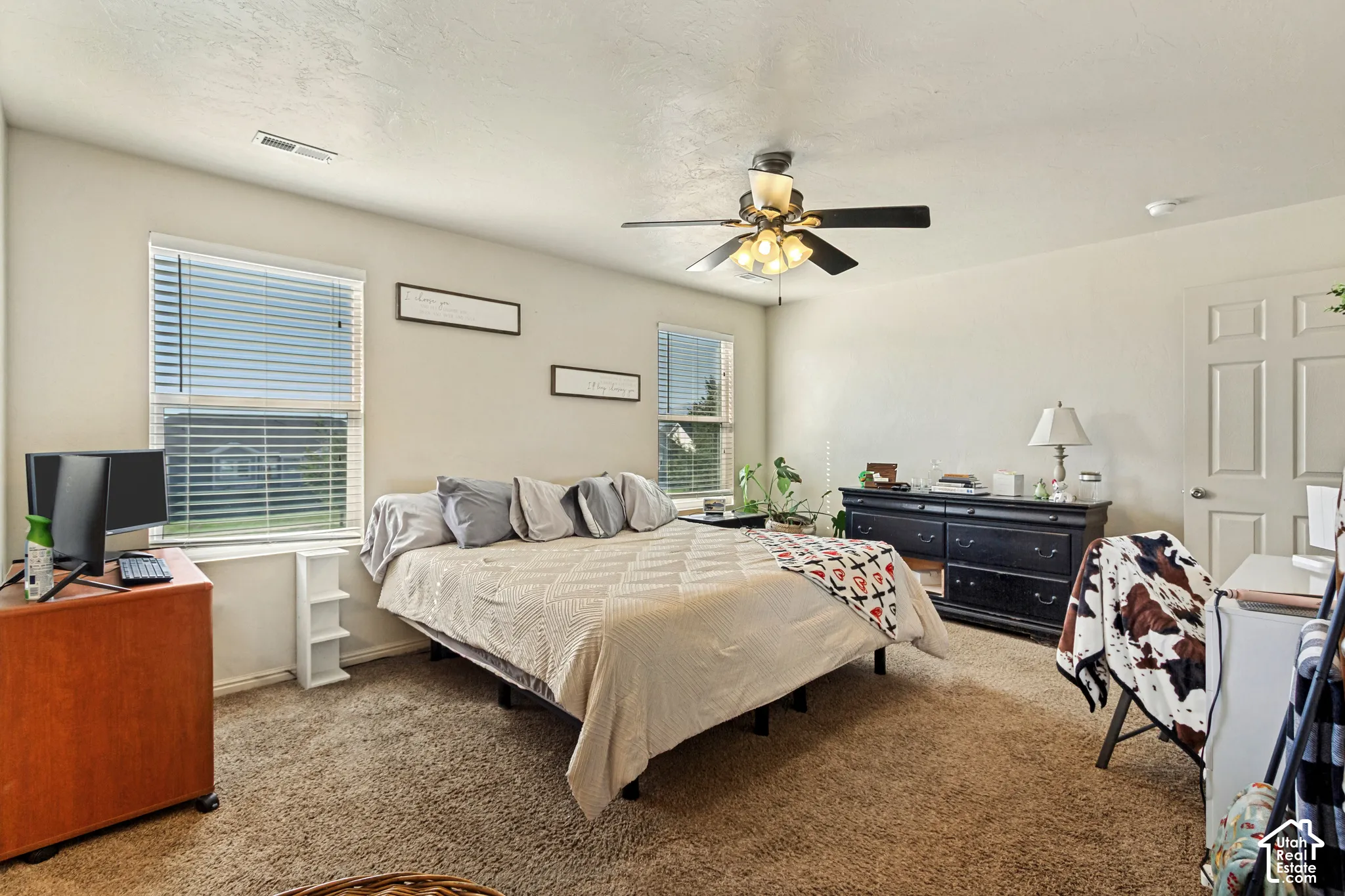 Carpeted flooring, ceiling fan with integrated lighting, multiple windows with blinds, and paneled door