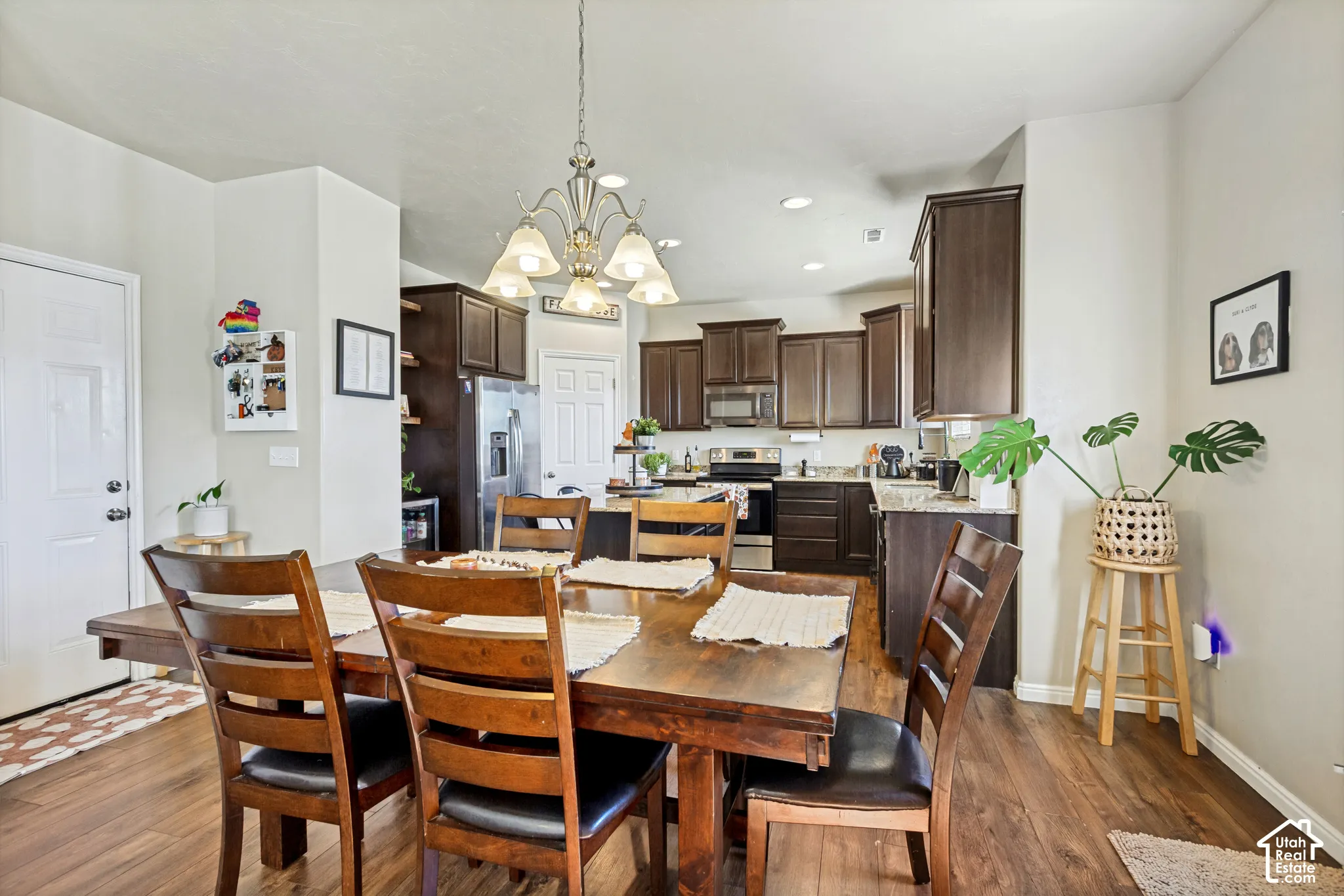 Dining space featuring a multi-bulb chandelier with frosted glass shades, wood-finish flooring, and light-toned walls