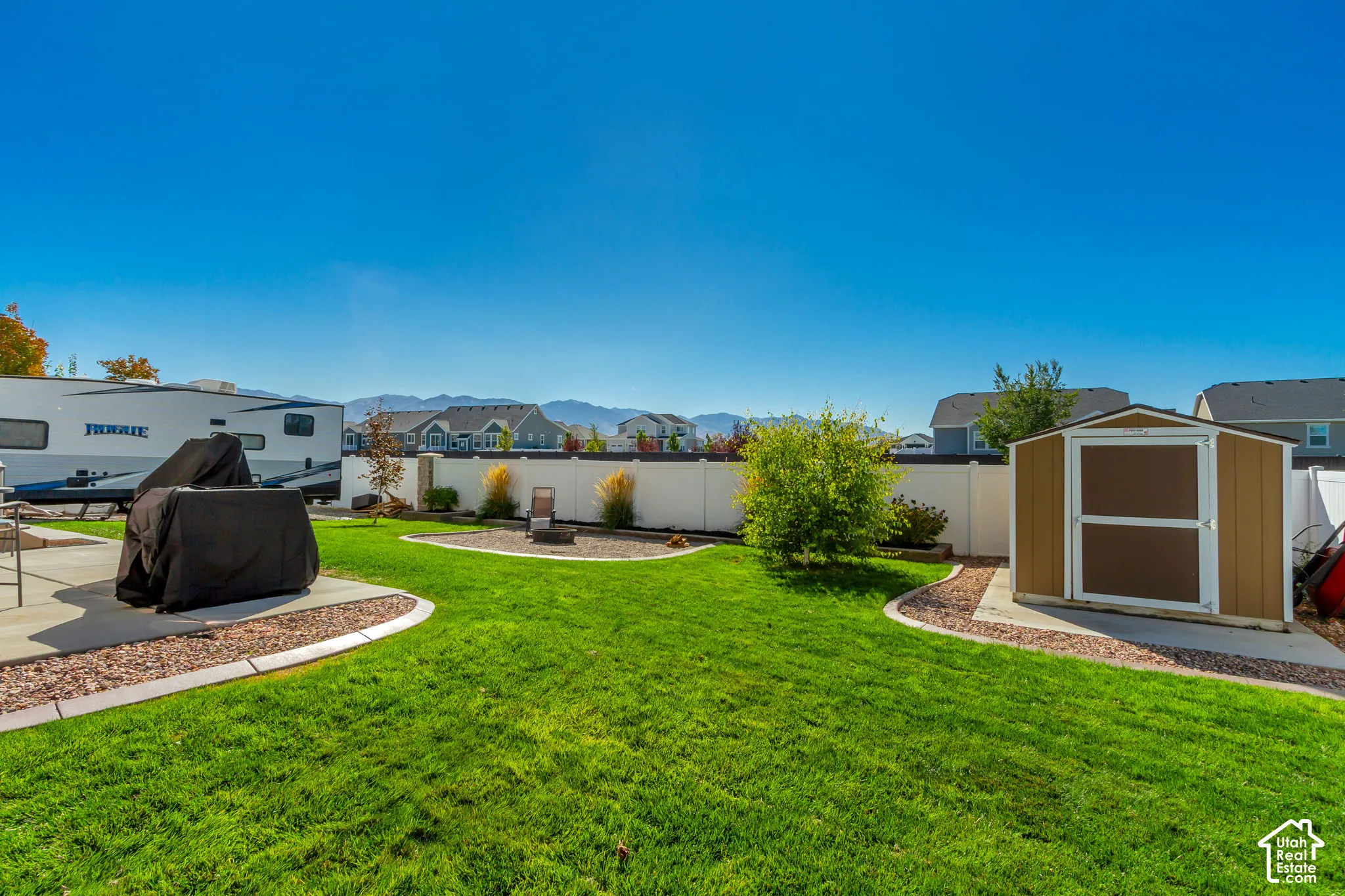 Expansive backyard featuring a concrete patio, a storage shed, and a privacy fence