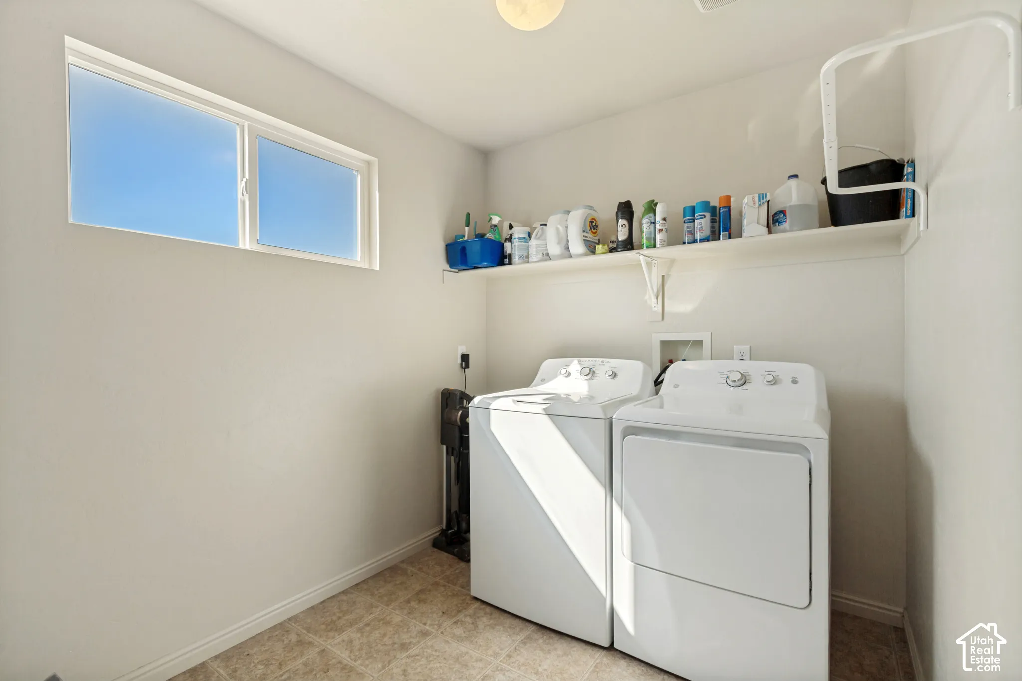 Utility room with a wide window, overhead shelving, and tiled flooring