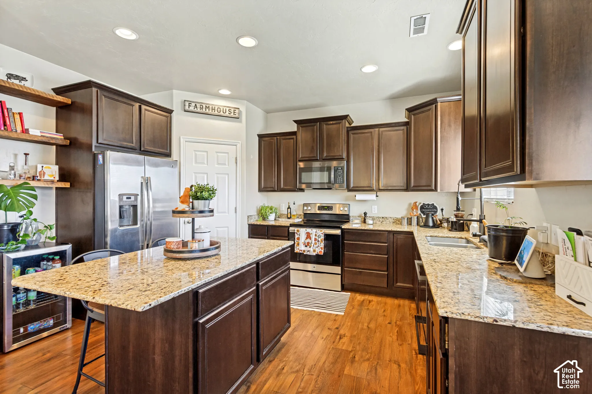 Kitchen featuring wood-finish flooring, recessed lighting, dark wood cabinetry, light-toned countertops, and a stainless steel appliance suite