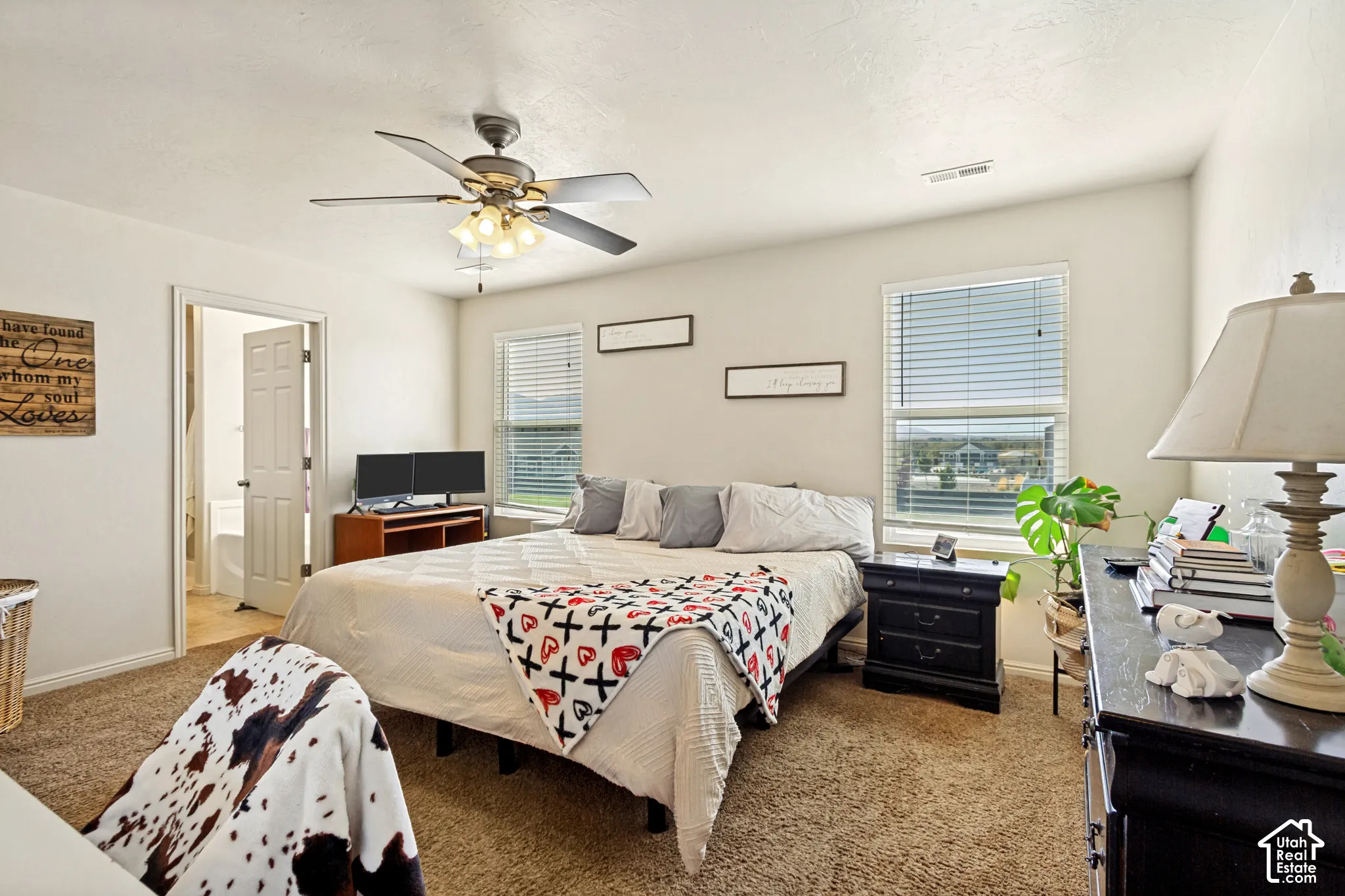 Carpeted room with a ceiling fan, two windows with blinds, and an interior door