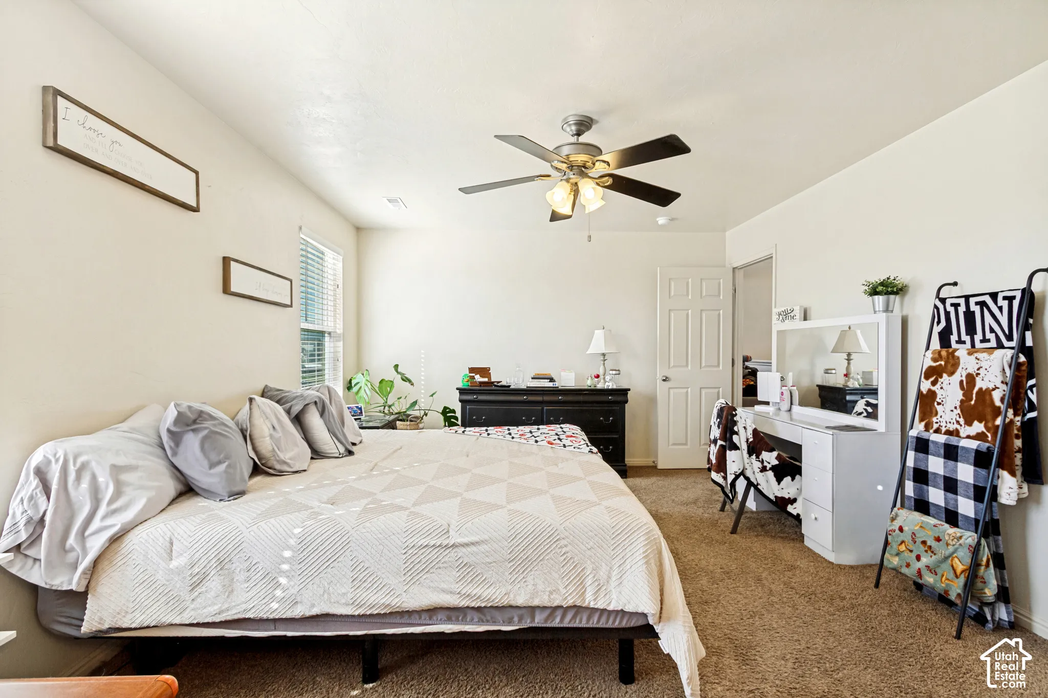 Carpeted bedroom featuring a ceiling fan with integrated lighting, a window with blinds, and white walls