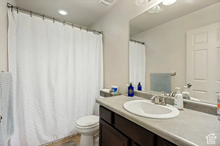 Spacious vanity with an integrated sink and brushed nickel faucet, large mirror, recessed ceiling lighting, and a white paneled door