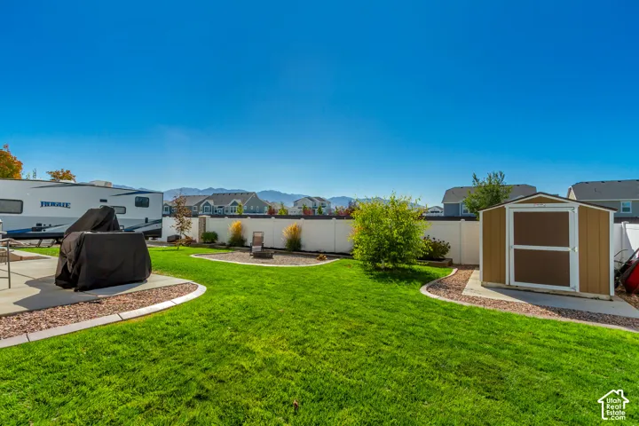 Expansive backyard featuring a concrete patio, a storage shed, and a privacy fence