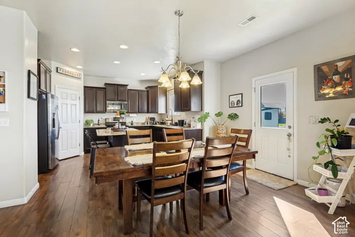 Open-concept dining area with wood-finish flooring, a contemporary chandelier, recessed lighting, and direct outdoor access