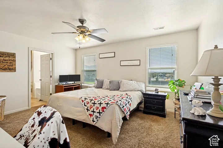 Carpeted room with a ceiling fan, two windows with blinds, and an interior door