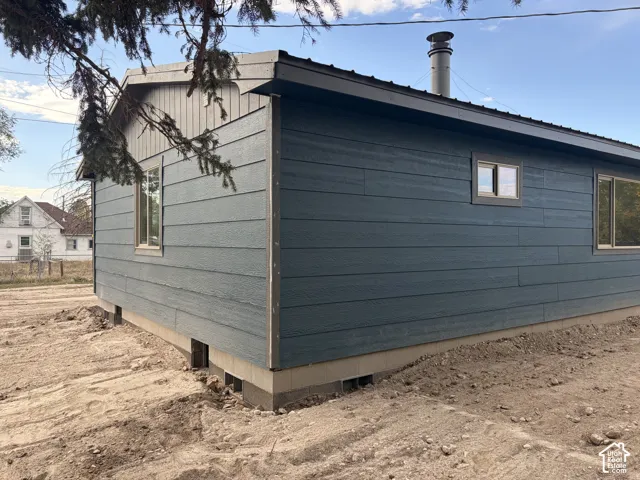 Dark blue horizontal siding with white trim, a dark metal roof, and a visible chimney