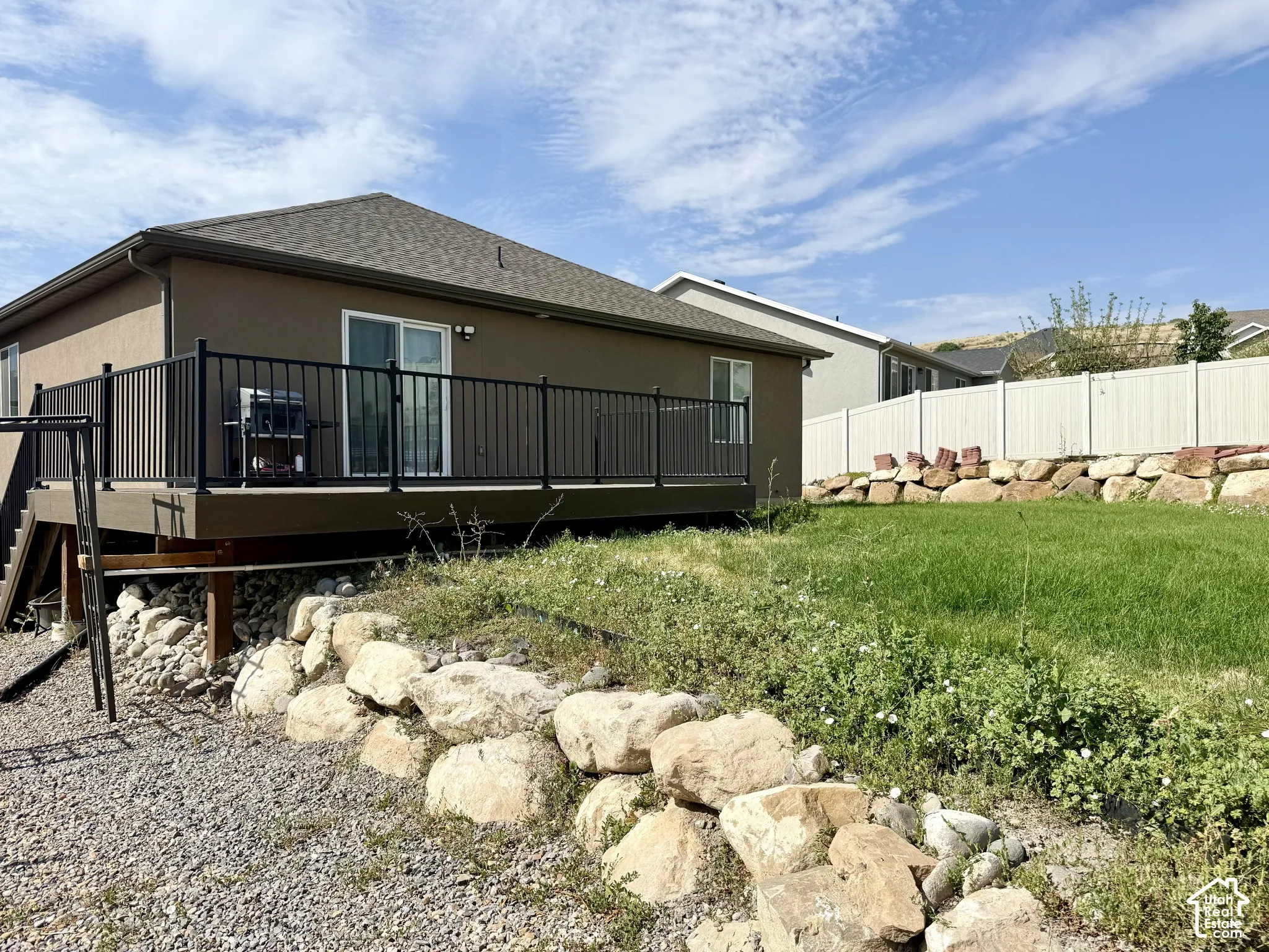 Rear exterior featuring a stucco finish, a deck with black metal railings, and a sliding glass door
