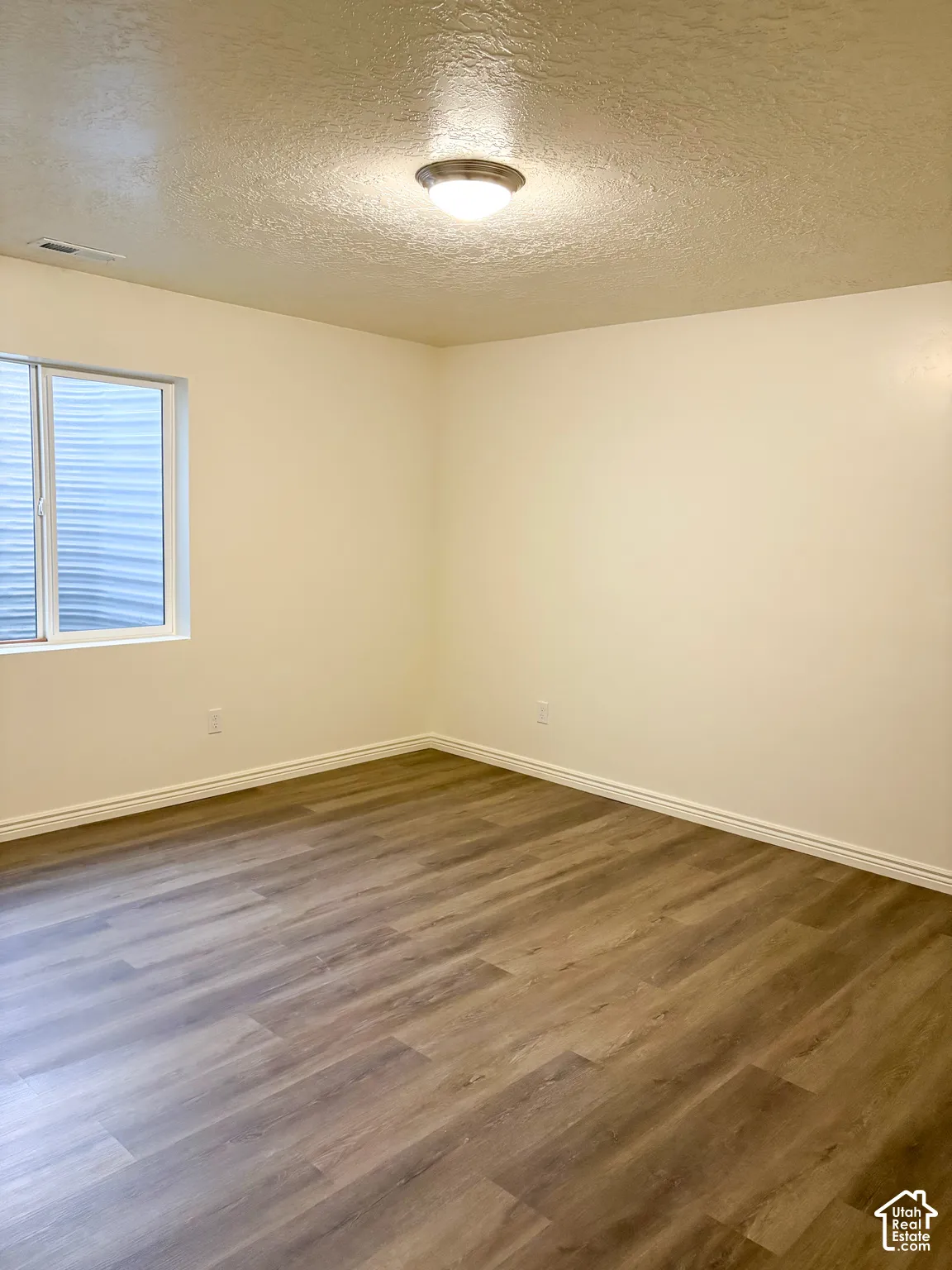 Wood-finish flooring with white baseboards and painted walls