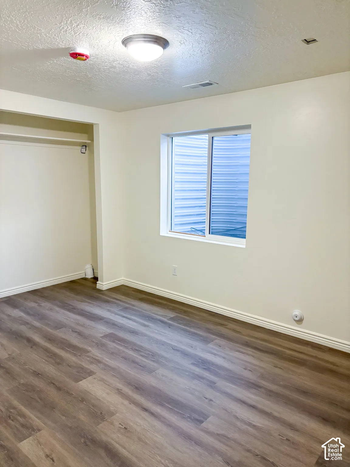 Wood-finish flooring, white walls, and a built-in closet with shelving