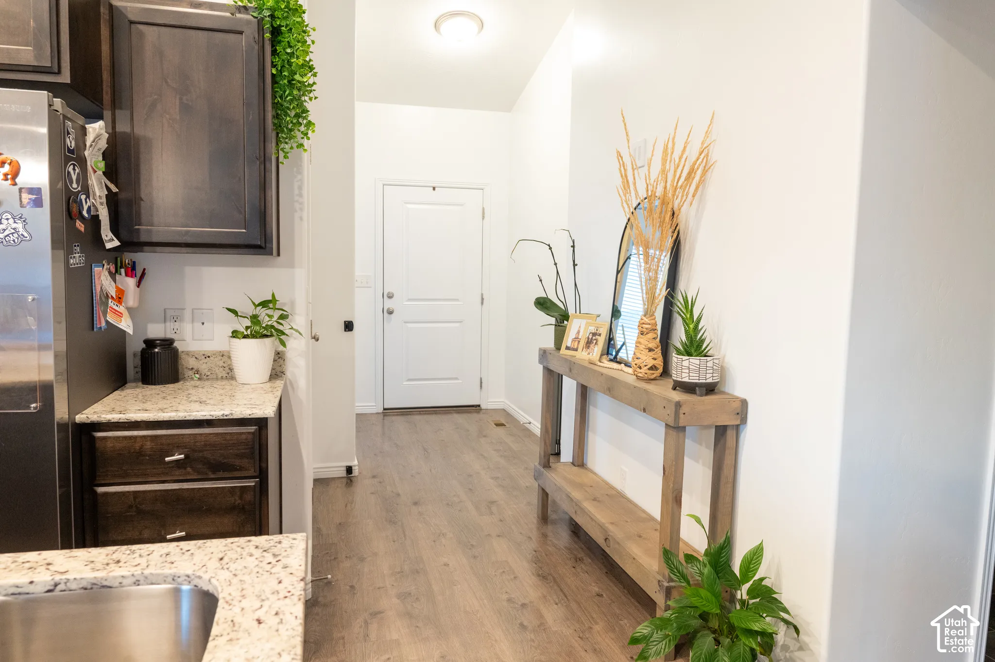 Wood-finish flooring, white walls, recessed ceiling lighting, and a white paneled entry door